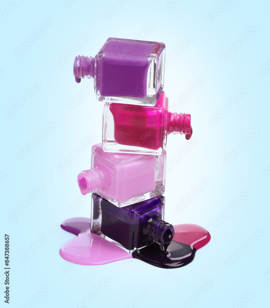 Different nail polishes dripping from open bottles on light blue background Different nail polishes dripping from open bottles on light blue background