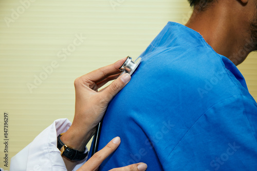 Close-up of doctor hand using stethoscope to listen to patient back in clinical examination, focusing on respiratory health