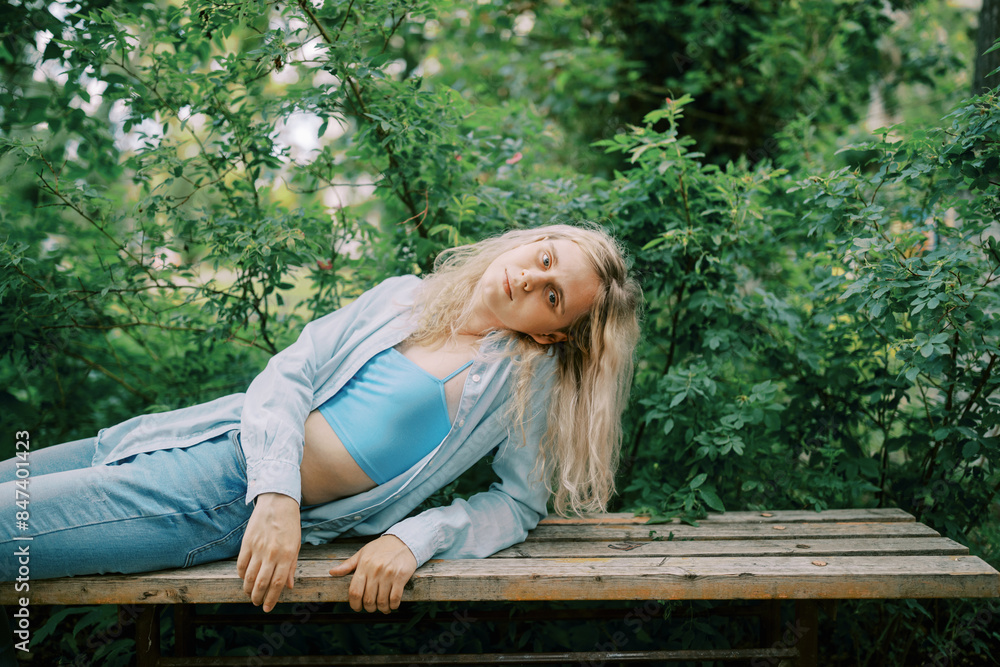 Transgender person wearing blue top and jeans relaxing on the bench Transgender person wearing blue top and jeans relaxing on the bench