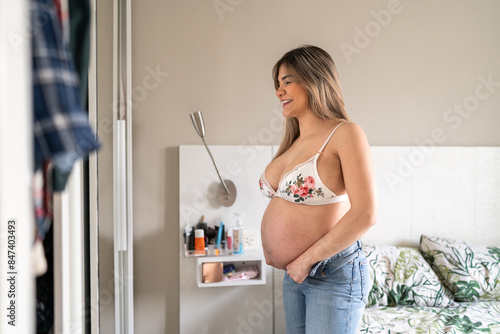 Pregnant woman having fun trying clothes.