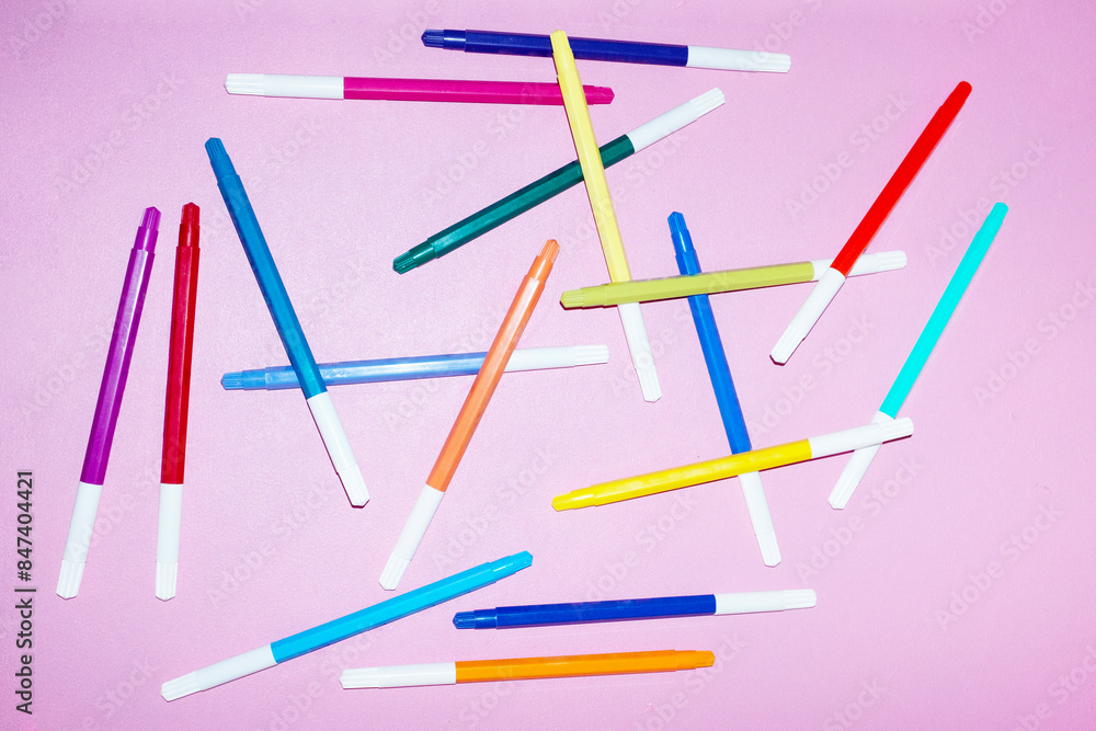 Colorful creative pens on pink background with hard direct flashlight Colorful creative pens on pink background with hard direct flashlight
