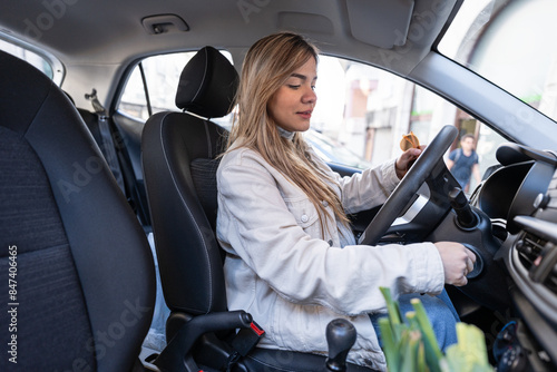 Pregnant woman enjoys a snack while confidently driving photo