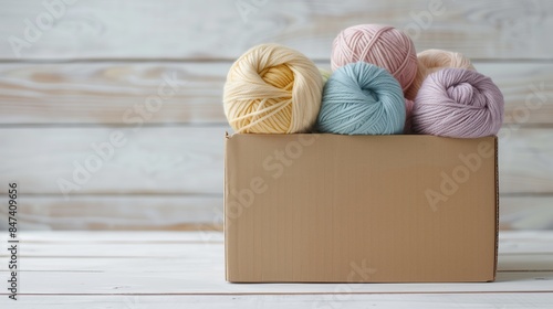 A cardboard box filled with dyed yarn skeins in soft pastel colors