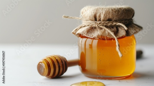 Bright and clean honey display, minimalistic design, isolated on a white background. Featuring a close-up of a jar of golden honey with a wooden dipper, the image captures elegance and natural sweetne photo