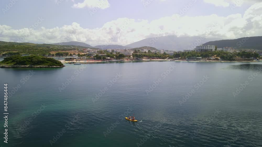 City of Ksamil in summer. Rowing tourists in a boat enjoying the sunny weather at a calm coast. Beautiful beaches of Albanian land City of Ksamil in summer. Rowing tourists in a boat enjoying the sunny weather at a calm coast. Beautiful beaches of Albanian land