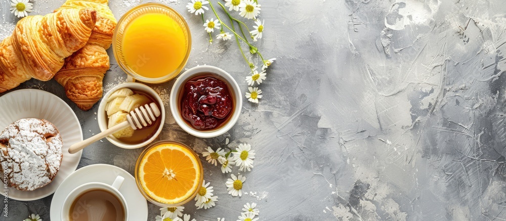 Captured from above: A delightful spread of continental breakfast items including coffee, orange juice, croissants, jam, honey, and flowers, set against a grey stone worktop with space for text. Captured from above: A delightful spread of continental breakfast items including coffee, orange juice, croissants, jam, honey, and flowers, set against a grey stone worktop with space for text.