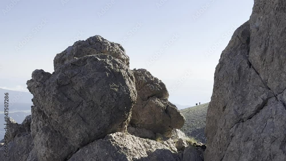 Sporty walks of a crowded group of climbers towards the summit, watched from among the rocks Sporty walks of a crowded group of climbers towards the summit, watched from among the rocks