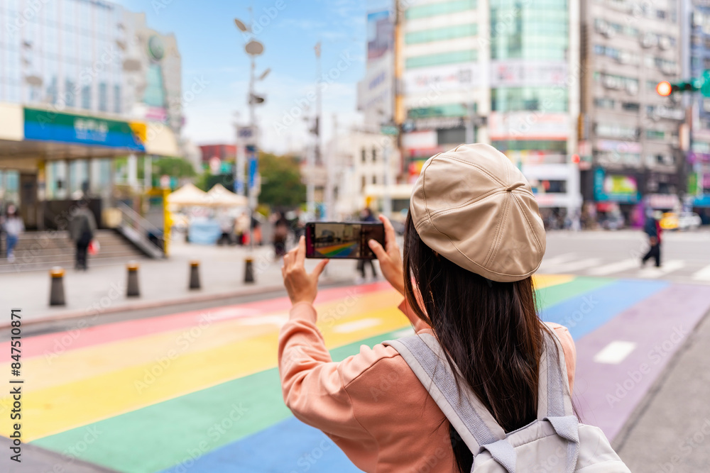 Naklejka premium Young female tourist taking a photo of the Rainbow Road crossing at ximending in Taipei, Taiwan