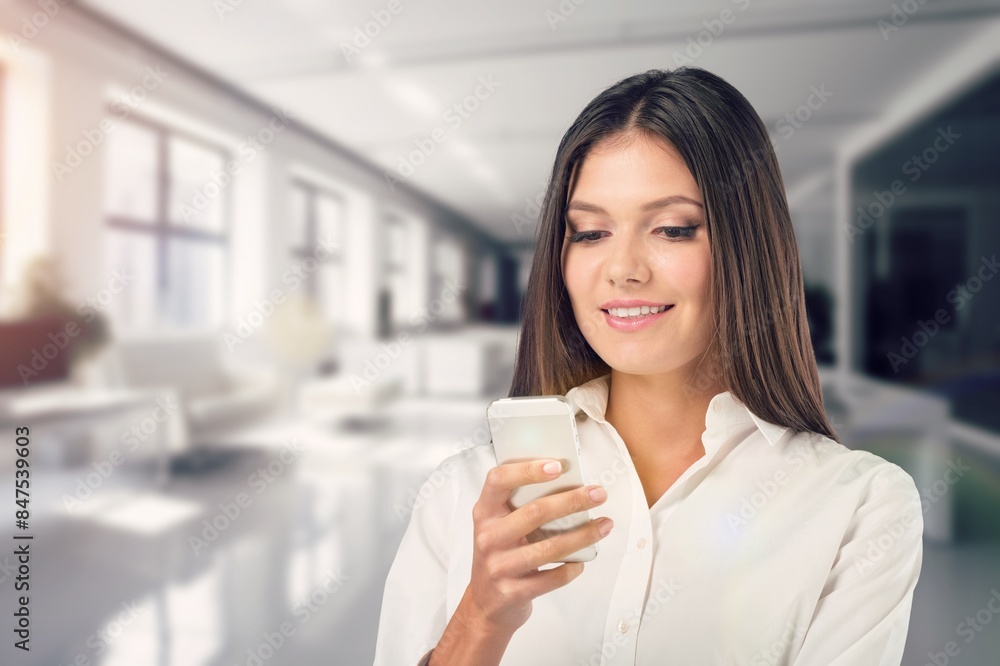 Smiling business woman with phone standing in office. Smiling business woman with phone standing in office.