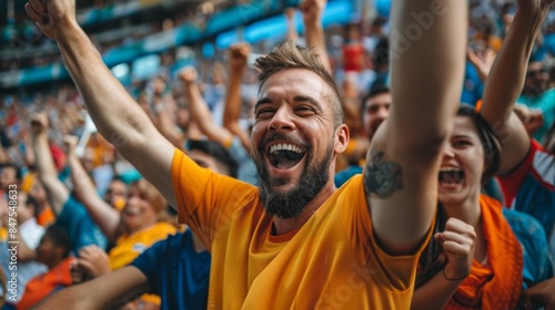 portrait of a joyful Caucasian fan in the colors of his team rejoices at his success while in a large football stadium crowded with fans