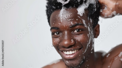 A man is washing his hair and smiling