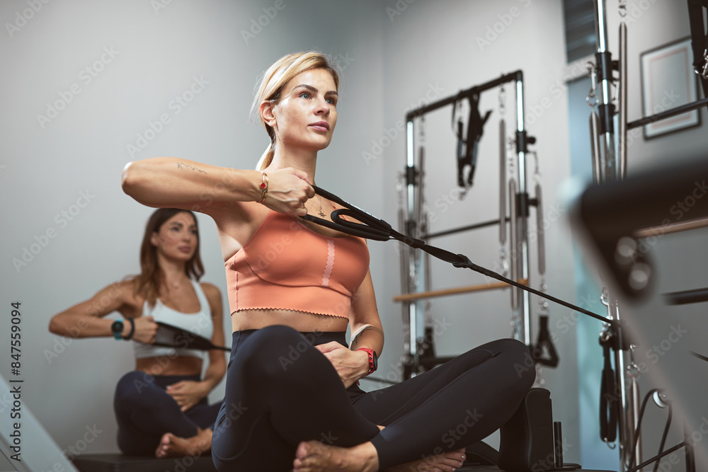 Fototapeta premium Young women exercising in a gym on pilates machines.