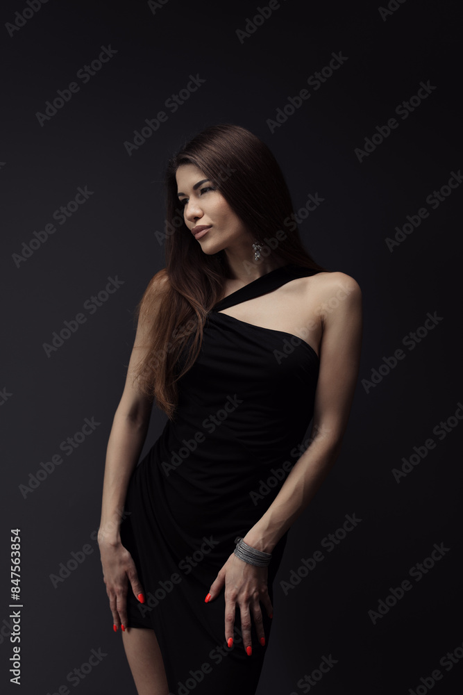 An elegant woman in a sophisticated black dress poses confidently against a dark backdrop. Her poised stance and stylish outfit exude luxury, style, and grace, perfect for high-fashion themes. An elegant woman in a sophisticated black dress poses confidently against a dark backdrop. Her poised stance and stylish outfit exude luxury, style, and grace, perfect for high-fashion themes.