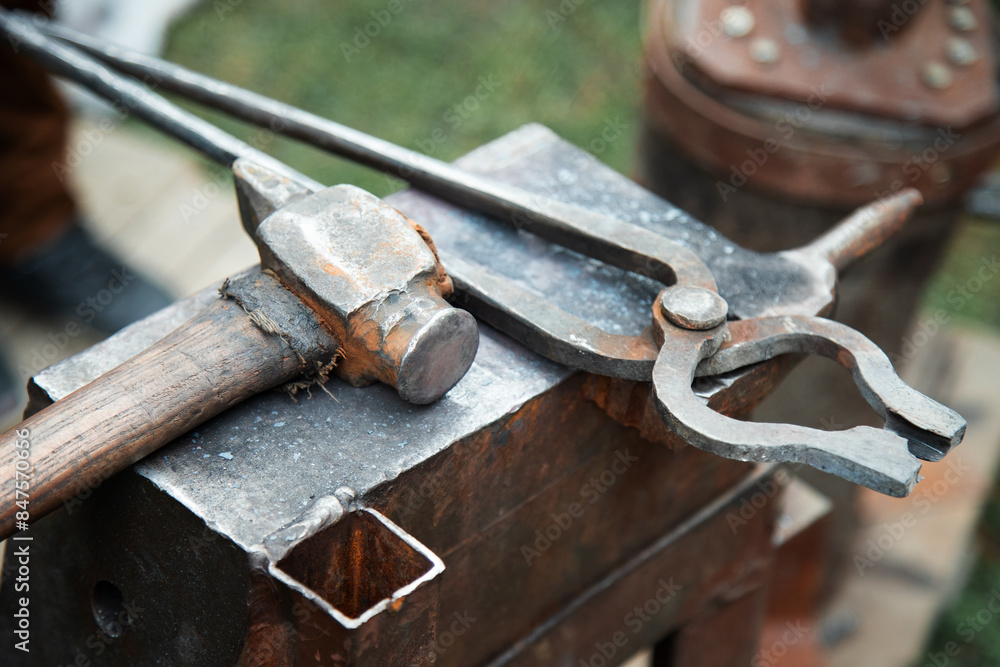 closeup of a blacksmith anvil with a hammer and pliers closeup of a blacksmith anvil with a hammer and pliers