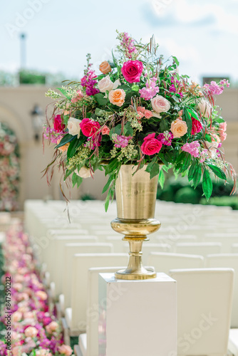 Florals in gold vase at outdoor wedding ceremony on sunny day © Cavan