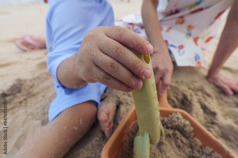 Close up of hand of asian young boy and mother playing sand and toy on beach Close up of hand of asian young boy and mother playing sand and toy on beach