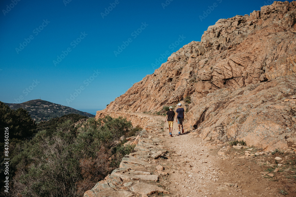 Two boys hiking in Corsica's rugged mountains overlooking the sea Two boys hiking in Corsica's rugged mountains overlooking the sea