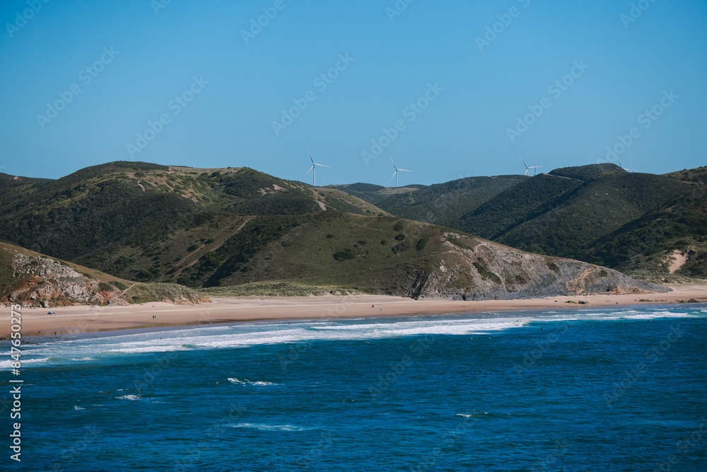 Wind turbines on green hills overlooking a beach in Algarve, Portugal Wind turbines on green hills overlooking a beach in Algarve, Portugal