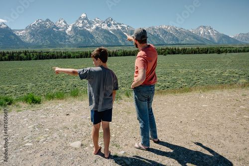 Father and son standing and pointing at Teton mountain range photo