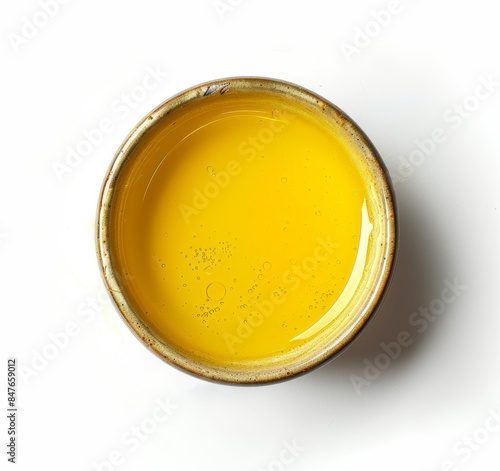 Top view of yellow liquid in a petri dish or glass with bubbles on a white background.
