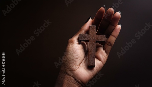 Wooden Christian Cross being held by Dark Skinned Hand - Symbol of Christianity - Believe and Faith in Christ or God - Praying or Wishing - Worshipping of Religion - Asking for Blessing from Above