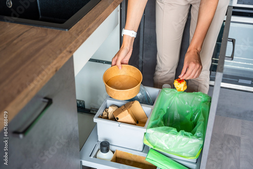 Konstfotografi Woman throwing trash into household bins for waste sorting in the kitchen for recycle