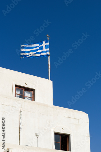 Greek flag on the building in a blue summer sky. Copy space.