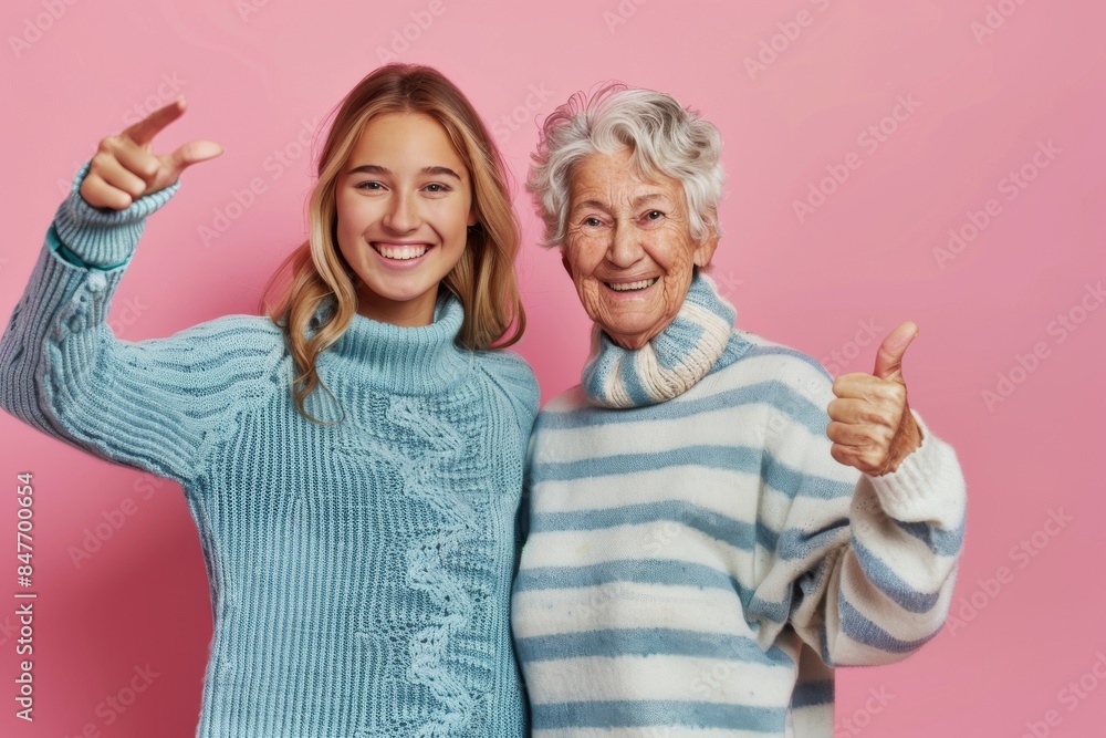 A 50-year-old mother with her 21-year-old daughter scream hot news, showing their thumbs up to the camera against a pink background on every other day, a family concept. A 50-year-old mother with her 21-year-old daughter scream hot news, showing their thumbs up to the camera against a pink background on every other day, a family concept.