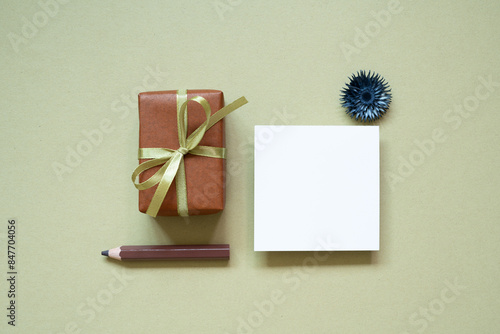 Obraz na płótnie Brown gift box, colored pencil, memo pad, dry flower on khaki background. top view w salonie
