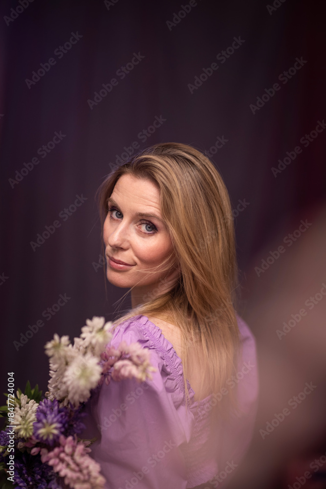 emotions of a pretty girl with lupine flowers in her hands on a dark background with colored light. emotions of a pretty girl with lupine flowers in her hands on a dark background with colored light.