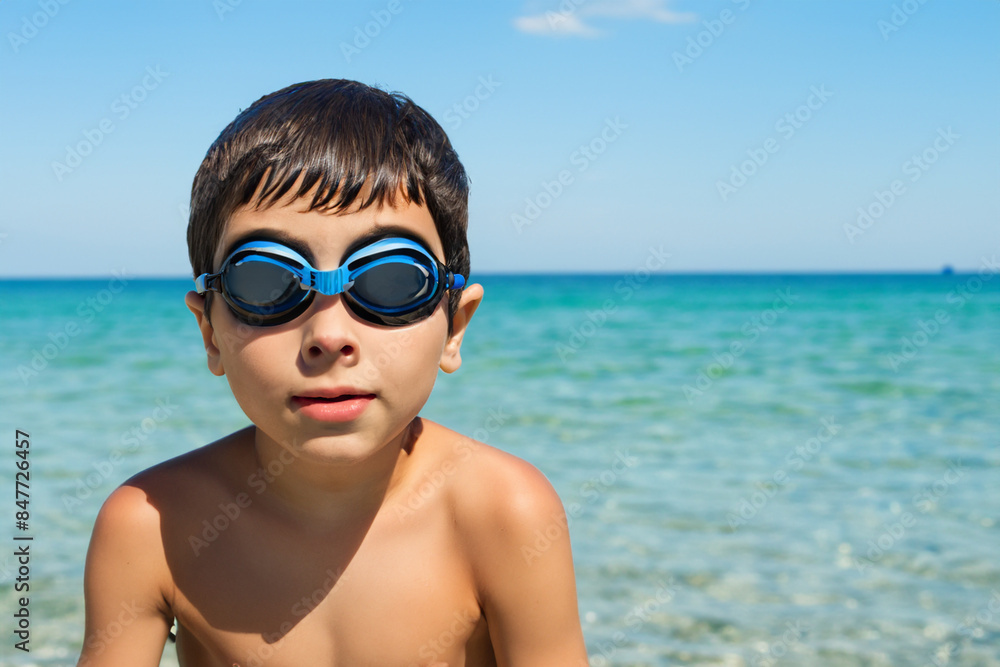 boy at sea. little tanned boy sitting against the background of the blue sea in blue swimming goggles, close-up vacation concept boy at sea. little tanned boy sitting against the background of the blue sea in blue swimming goggles, close-up vacation concept