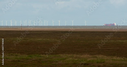 Wide shot of tidal mud flats with wind turbines and cargo ship in background at Saltfleet, Louth, Lincolnshire. photo