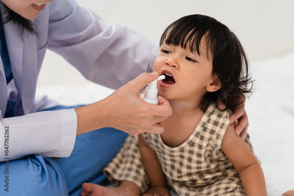doctor spraying medicine in mouth of toddler. baby sore throat treatment concept doctor spraying medicine in mouth of toddler. baby sore throat treatment concept