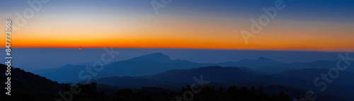 amazing dramatic cloudscape in sunset with sun rays over misty blue mountains landscape  