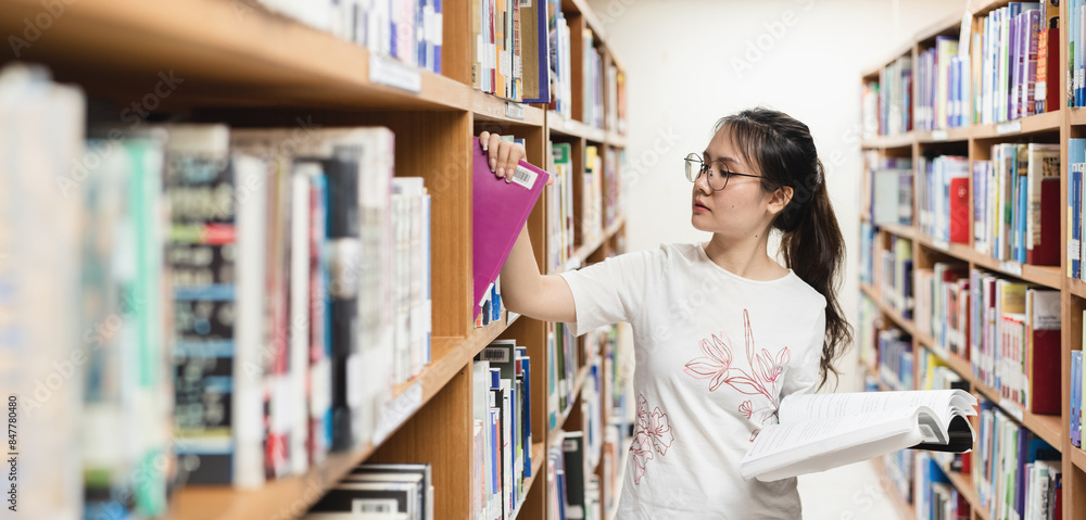 A student reading and selecting a book from a library shelf, ideal for educational and academic-themed designs, back-to-school promotions, and study-related events. A student reading and selecting a book from a library shelf, ideal for educational and academic-themed designs, back-to-school promotions, and study-related events.
