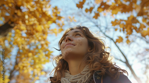 Young woman looking up at fall foliage on a sunny day