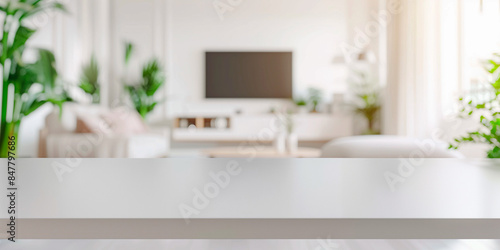 frontal view shot of empty white table in living room, white blurred living room with tv and furniture in the background