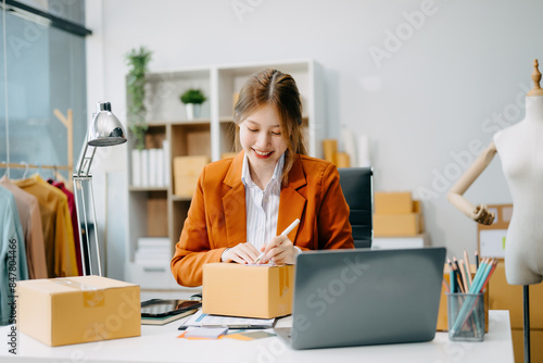 Young business owner woman prepare parcel box and standing check online orders for deliver