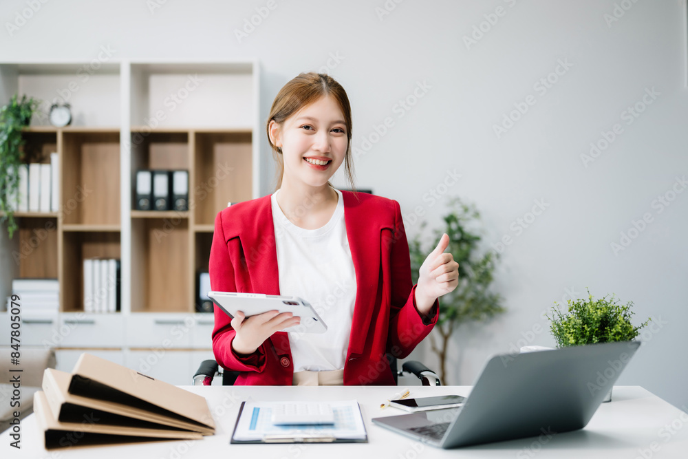 Confident Asian woman with a smile standing holding notepad and tablet at the ffice.. Confident Asian woman with a smile standing holding notepad and tablet at the ffice..