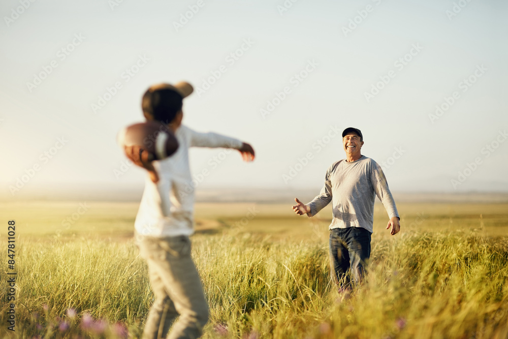 Father, son or American football in nature for bonding, skills practice with dad in outdoor. Male person, boy child and development or training in countryside, together for exercise or learning sport Father, son or American football in nature for bonding, skills practice with dad in outdoor. Male person, boy child and development or training in countryside, together for exercise or learning sport