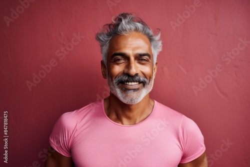 Portrait of a satisfied indian man in his 60s donning a trendy cropped top isolated on vibrant yoga studio background