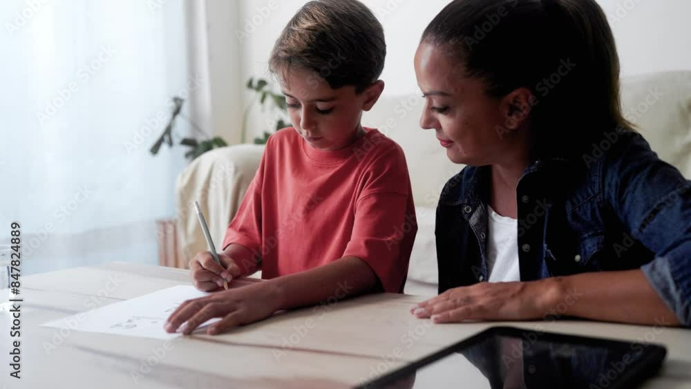 Mother and son doing homework for elementary school at home. Parent help child boy with education project Mother and son doing homework for elementary school at home. Parent help child boy with education project