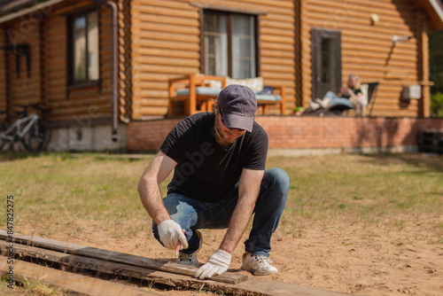 A man doing chores in his backyard - cutting boards for a fence