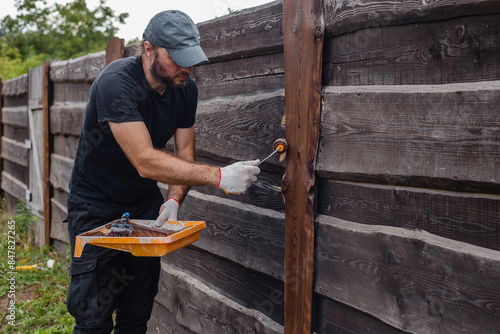A man builds a wooden fence from boards - rough unedged board for a picket fence