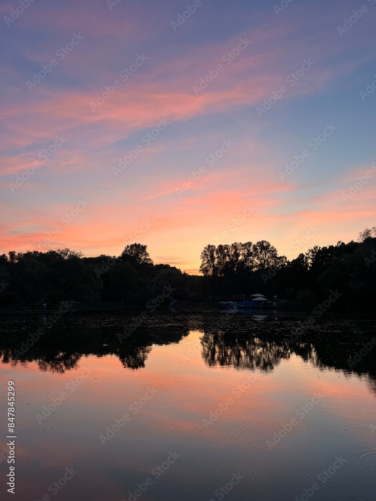 Purple sky reflection on the water surface, lake in park, silhouettes of the trees reflection Purple sky reflection on the water surface, lake in park, silhouettes of the trees reflection