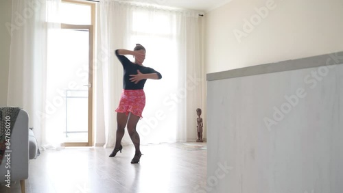 4K video of sexy woman in  black and pink skirt solo dancing Flamenco dance in her living room. Her active hips and arm movements transport her to lively streets of Spain, exuding freedom and energy