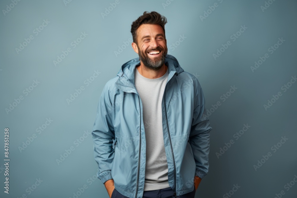 Portrait of a cheerful man in his 30s wearing a functional windbreaker in front of minimalist or empty room background Portrait of a cheerful man in his 30s wearing a functional windbreaker in front of minimalist or empty room background