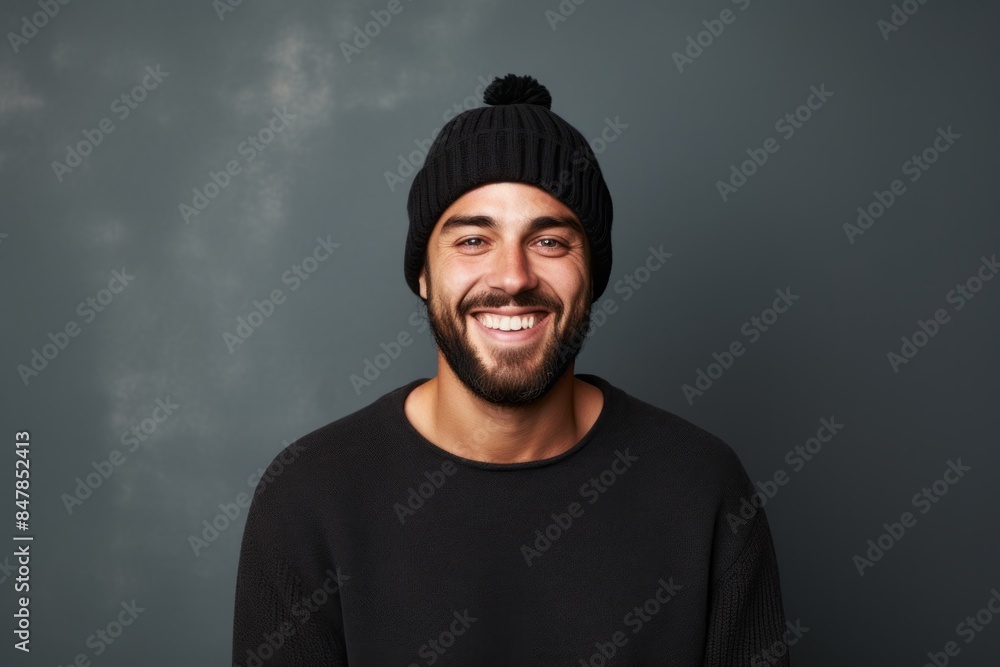 Portrait of a grinning man in his 30s donning a warm wool beanie over minimalist or empty room background Portrait of a grinning man in his 30s donning a warm wool beanie over minimalist or empty room background