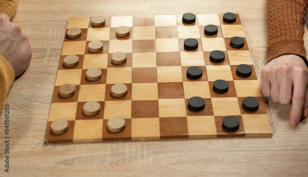 Board game of checkers. Chess field. Close-up of Checkers move. hand near checker Board game of checkers. Chess field. Close-up of Checkers move. hand near checker