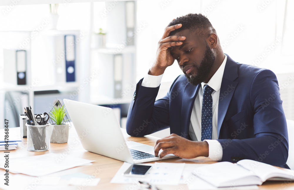 © Prostock-studio - Exhausted young african american entrepreneur working with laptop in office, touching his forehead, copy space © Prostock-studio - Exhausted young african american entrepreneur working with laptop in office, touching his forehead, copy space